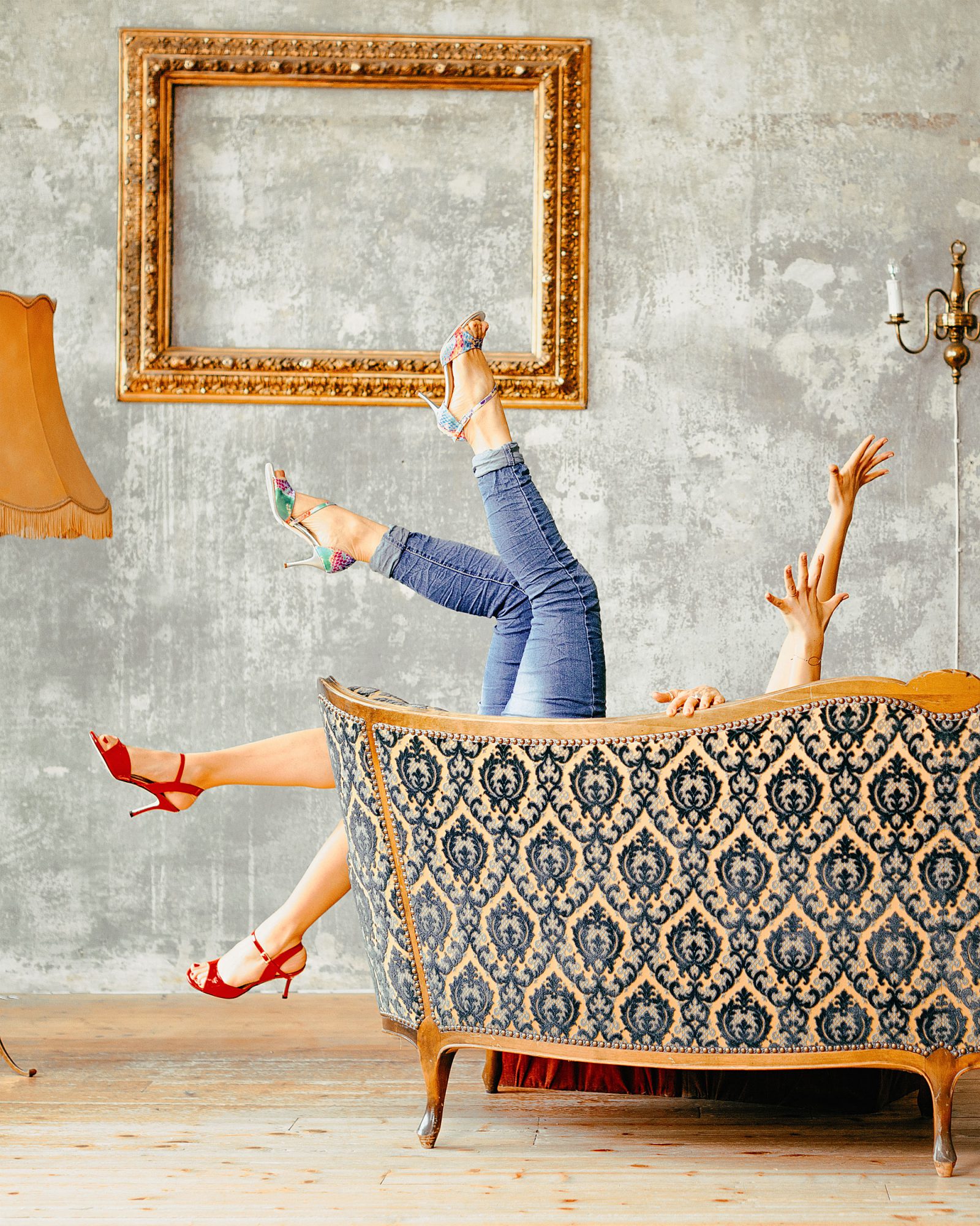 Hilfe! Von einem Sofa ragen zwei Paar in die Höhe gestreckte Hände und Beine mit Tangoschuhen
